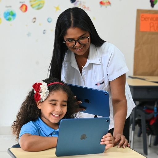 Imagen institucional de una docente del Colegio La Salle guiando a una estudiante en el uso de herramientas digitales dentro del aula, destacando la innovación educativa, el acompañamiento pedagógico, el aprendizaje interactivo, la tecnología educativa y la formación integral.
