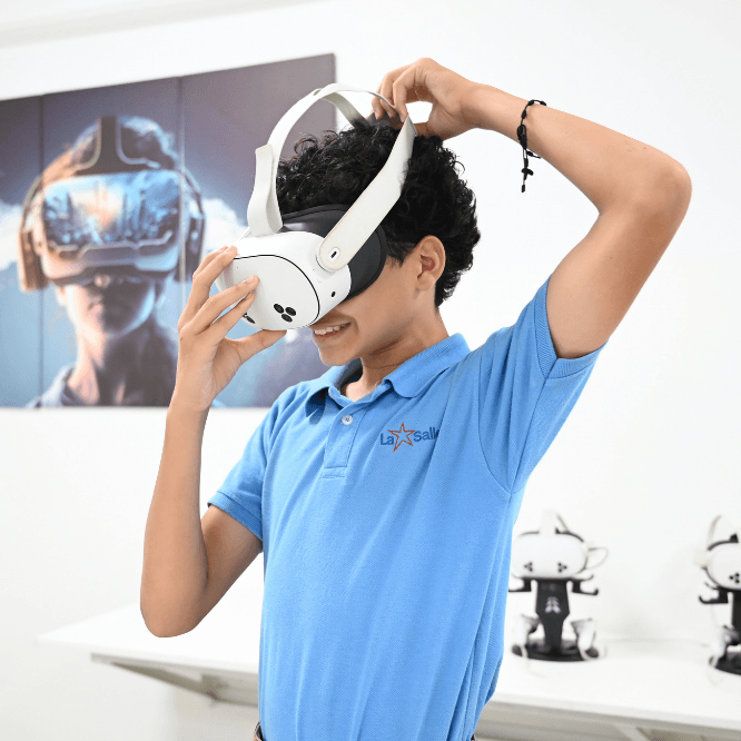 Estudiante del Colegio La Salle con uniforme azul se coloca un visor de realidad virtual en un espacio educativo relacionado con tecnología.